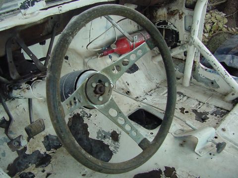 1969 Ford Mustang - The interior of a car shows significant wear and tear, with a fire extinguisher visible.