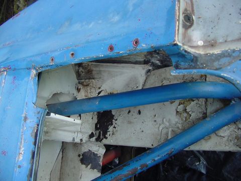 1969 Ford Mustang - Close-up view of a blue vehicle's interior, revealing a roll cage and weathered metal components.