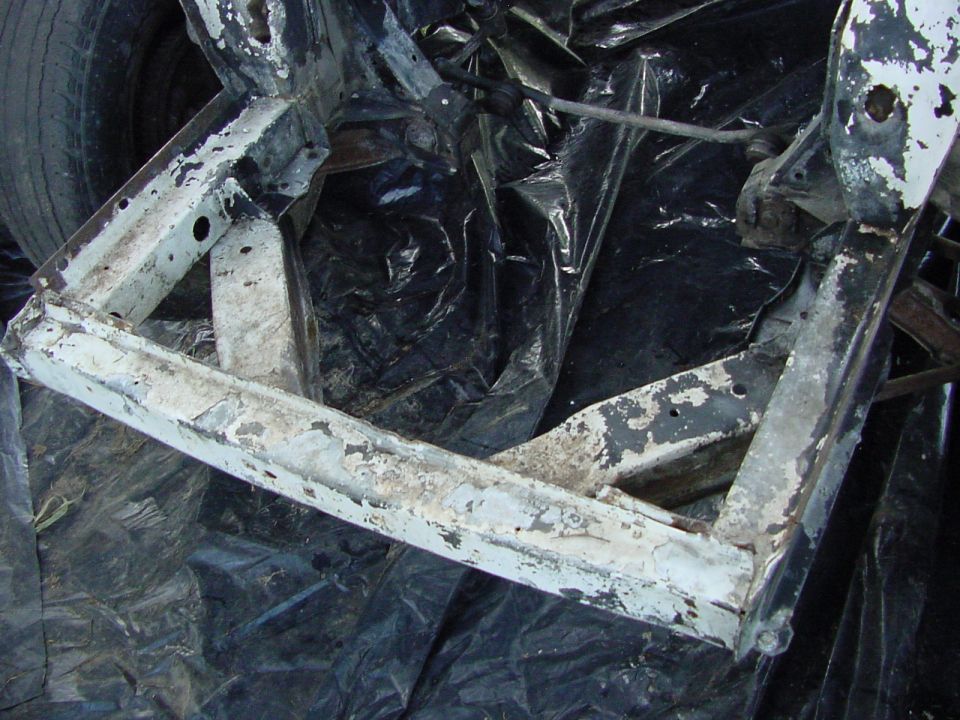 Car frame with white and black paint, on black plastic sheeting