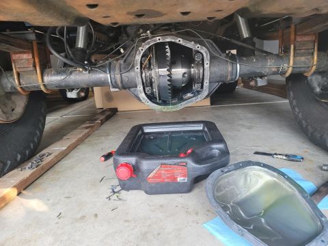 1996 Ford Bronco - The rear differential of a 1996 Ford Bronco is exposed for maintenance, with a drain pan ready to collect old fluid.