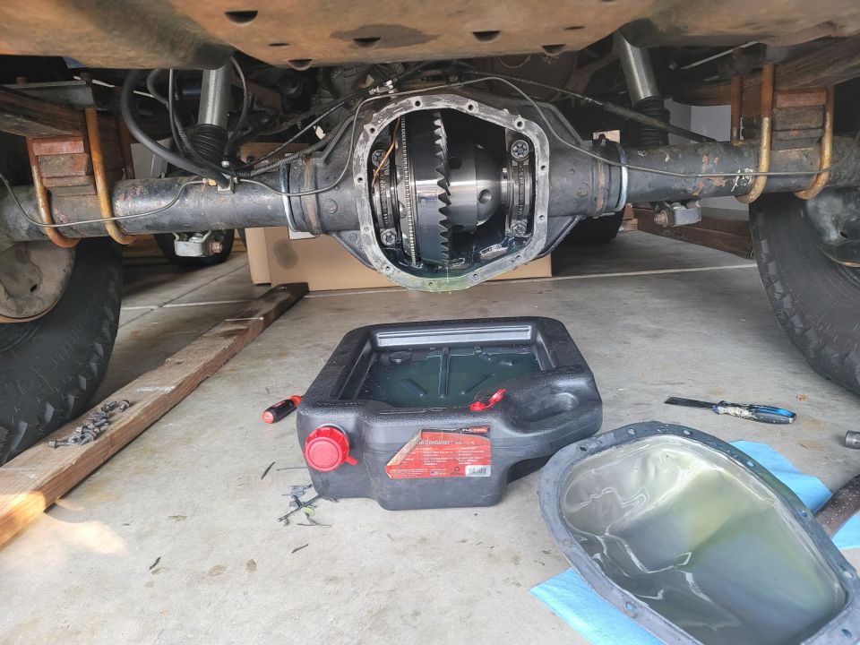 Rear differential cover removed from a 1996 Ford Bronco, with a drain pan and tools nearby