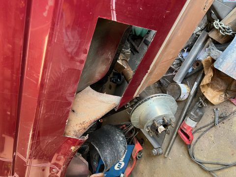 1995 Ford Bronco - A red vehicle panel shows a large cut-out, revealing internal components and surrounding tools and parts.