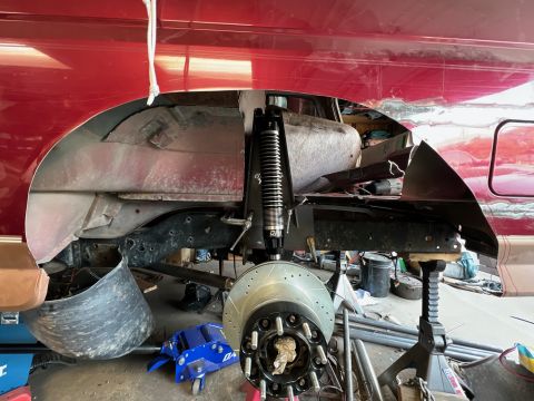 1995 Ford Bronco - The rear suspension of a vehicle is undergoing maintenance, with a new shock absorber and brake rotor visible.