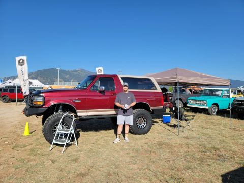 1996 Ford Bronco - Modified red 1996 Ford Bronco at an outdoor event with other vehicles present.