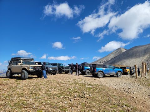 1996 Ford Bronco - A group of off-road vehicles gathered on a mountain pass with scenic views.