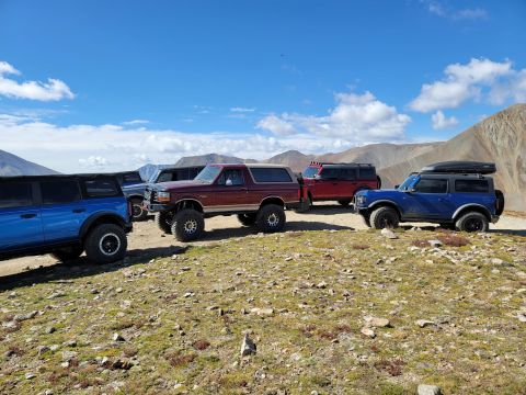 1996 Ford Bronco - A group of Ford Broncos are gathered on a scenic mountain overlook, their off-road capabilities.