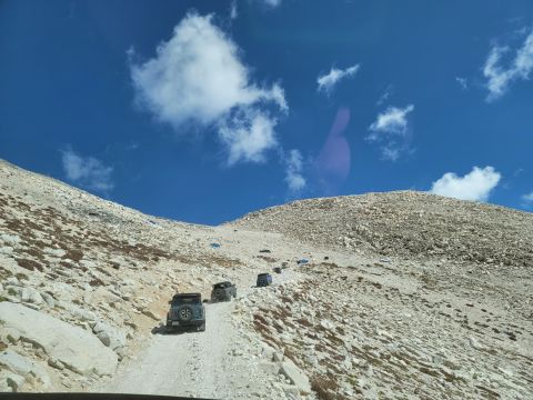 1996 Ford Bronco - Several SUVs navigate a challenging, rocky incline on a bright, clear day.