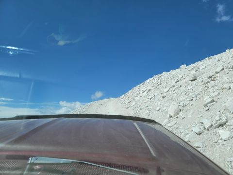 1996 Ford Bronco - View from inside a maroon vehicle driving on a rocky road towards a bright blue sky.