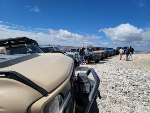 1996 Ford Bronco - A group of Ford Broncos are lined up in a desert setting with people gathered around.