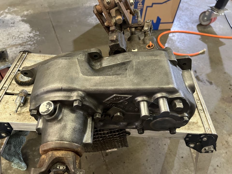 Jeep transfer case with linkage, resting on a metal stand. Part number visible