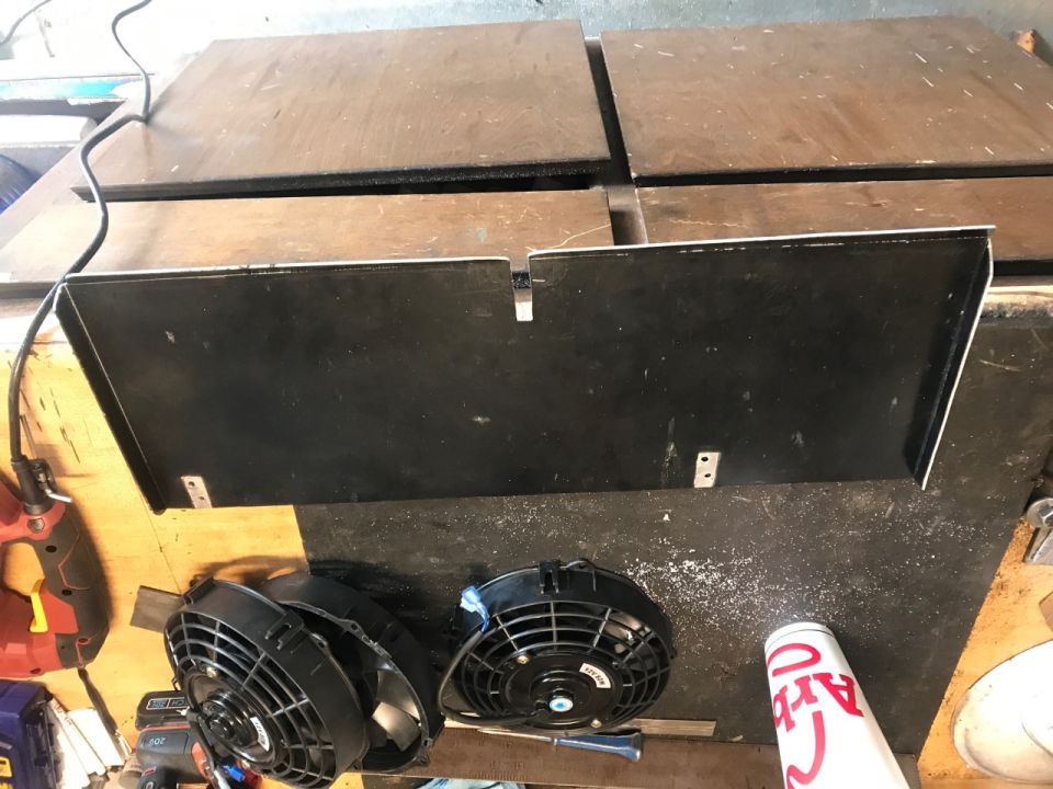 Two engine cooling fans and a black shroud on a workbench