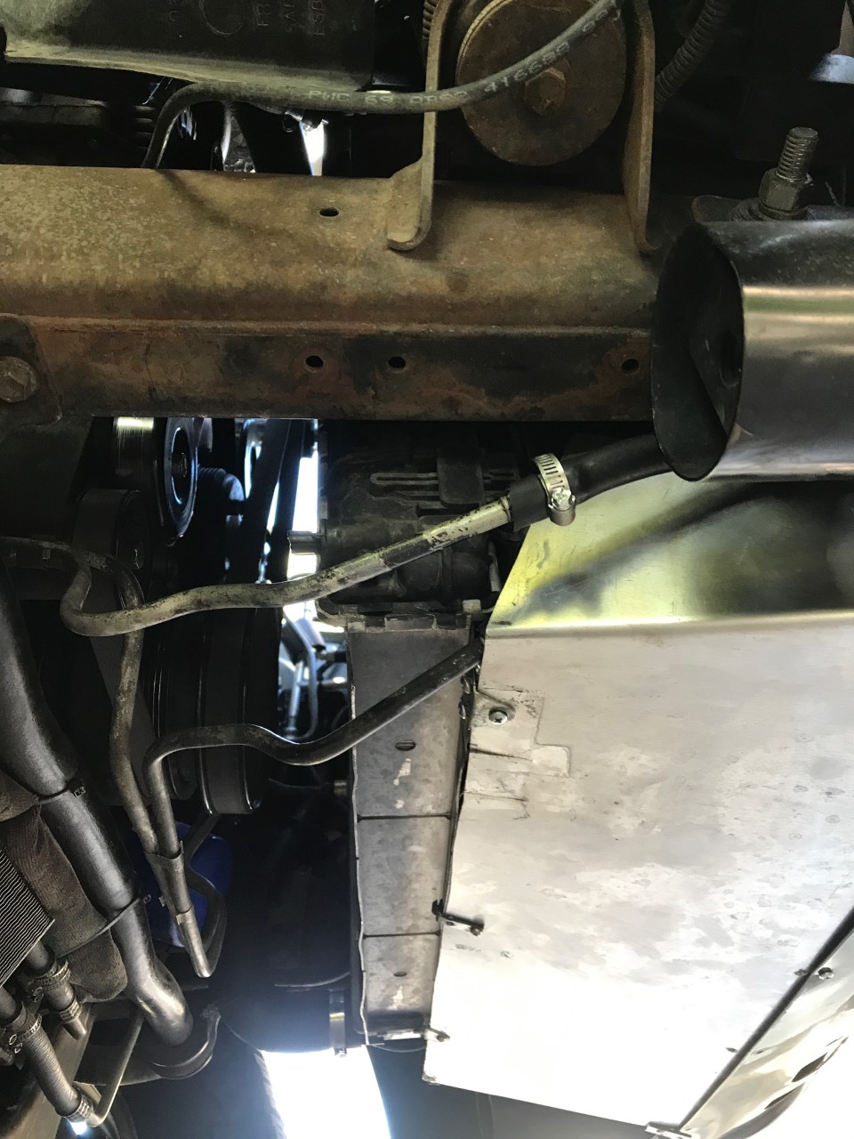 Underside view of engine bay with hoses and metal shielding visible