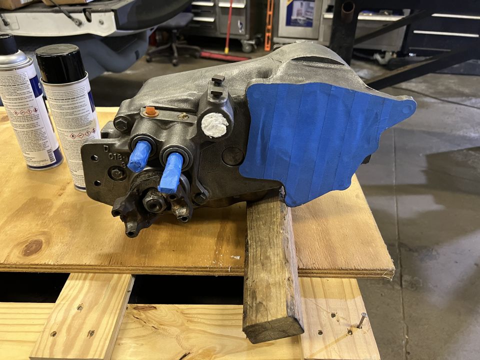 transmission part on wooden support, with spray cans nearby