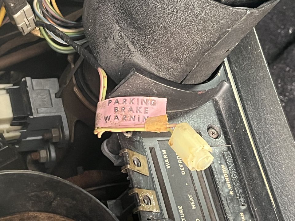 Interior dashboard with pink parking brake warning sticker and wiring