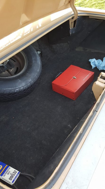 1972 Buick LeSabre - The trunk of a car contains a spare tire, a red toolbox, and a new automotive belt.