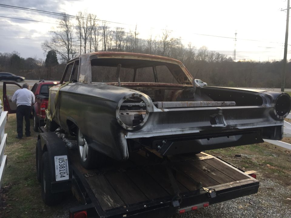 1963 Ford Galaxie body on a trailer, showing rear end with round taillight openings and no lights. The car is stripped down and appears to be undergoing restoration