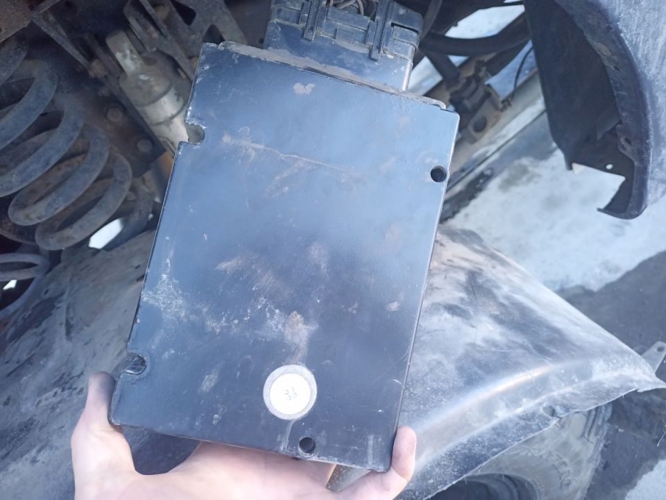 Hand holding black vehicle control module with wiring harness connector