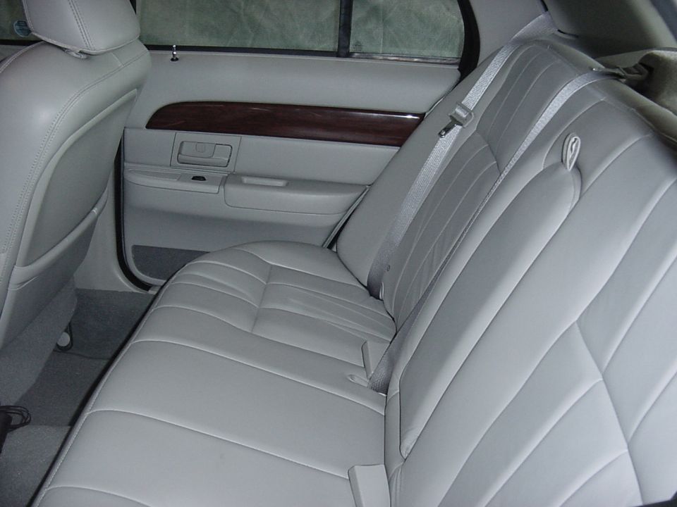 Light gray leather rear bench seat and woodgrain door trim in a full-size sedan