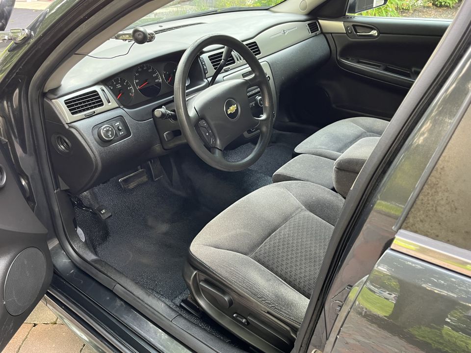 Interior of a Chevrolet Impala sedan, showing dashboard, steering wheel, and front seats.