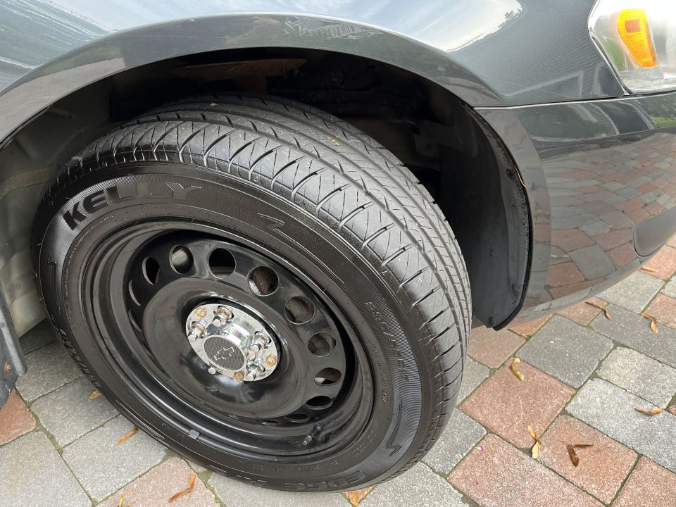Close-up of a dark gray car's front passenger tire and steel wheel with a Chevrolet center cap.