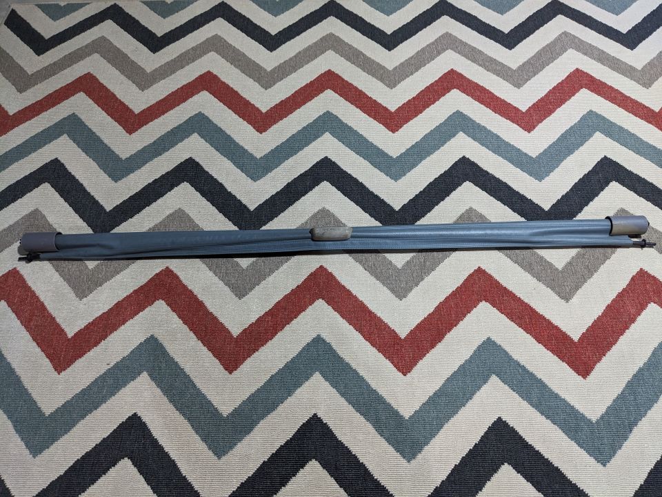Rolled-up dark gray car sunshade on a chevron patterned rug.