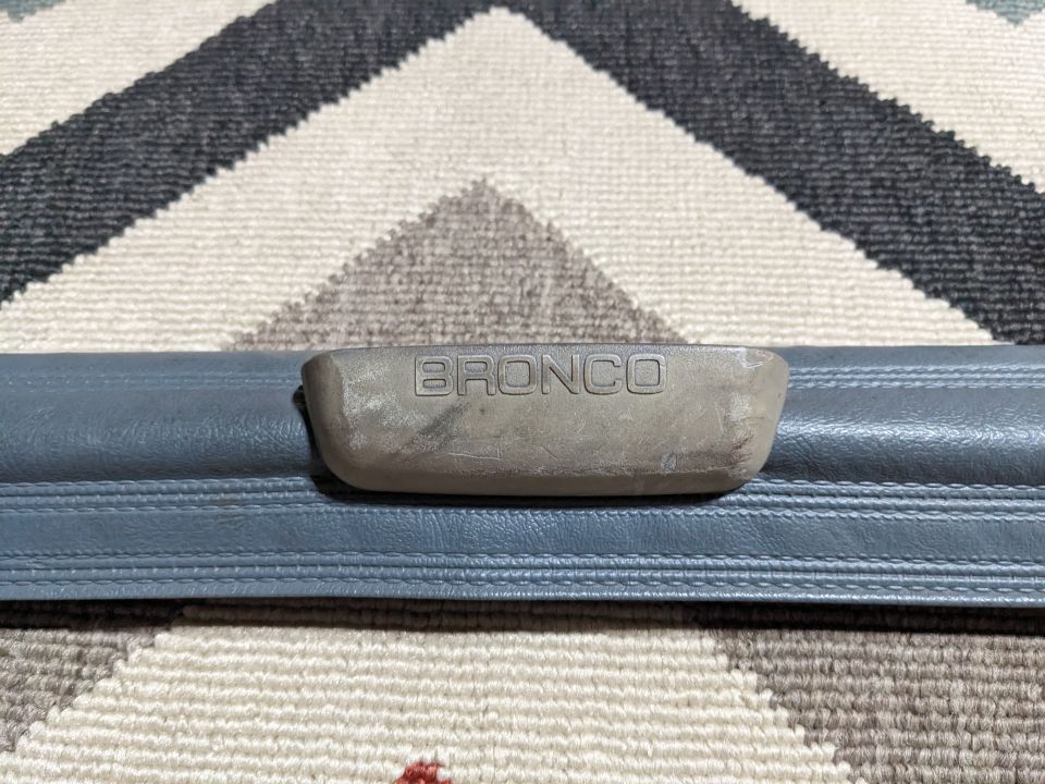 Embossed Bronco trim piece on gray plastic.