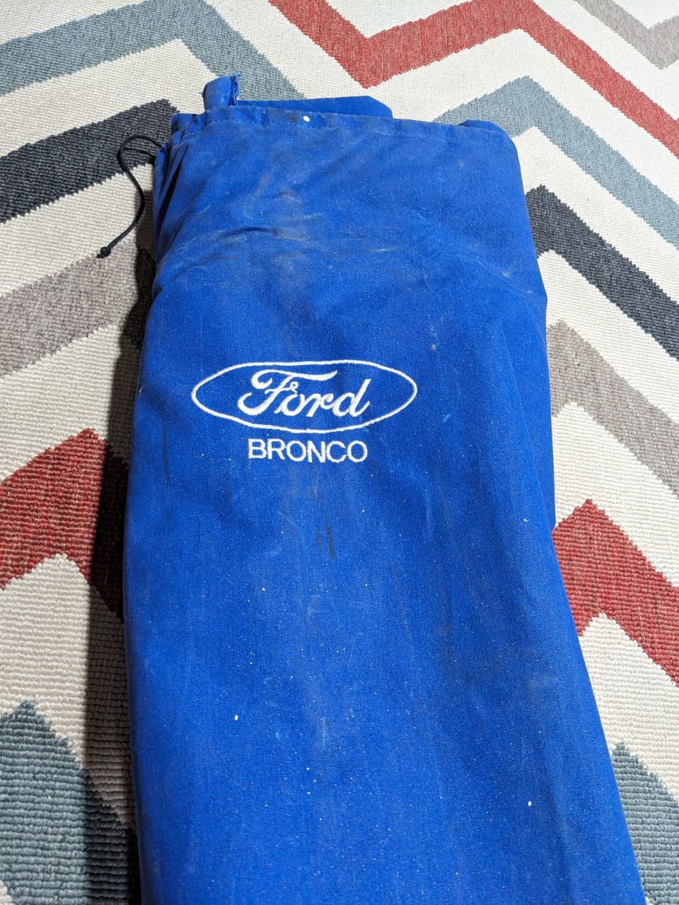 Blue Ford Bronco storage bag on a patterned rug.