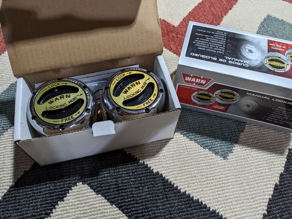 Two Warn manual locking hubs in a box, with a third box visible.