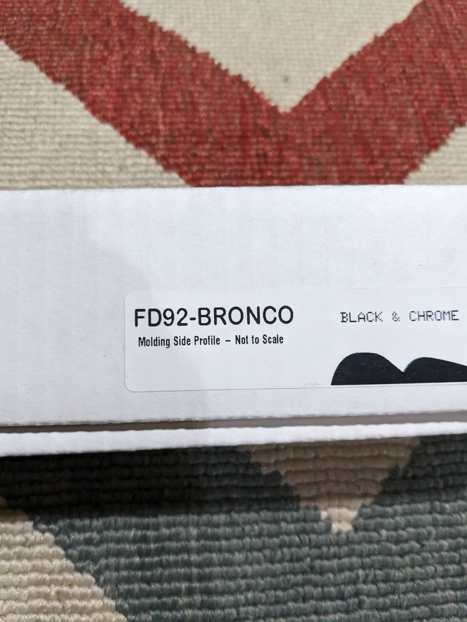White box with text FD92-BRONCO Molding Side Profile - Not to Scale, BLACK & CHROME on a patterned surface.