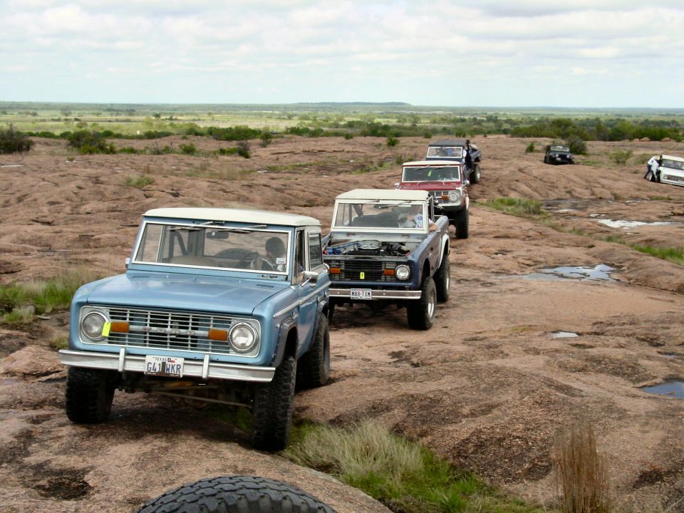 Line of Ford Broncos driving on rocky terrain