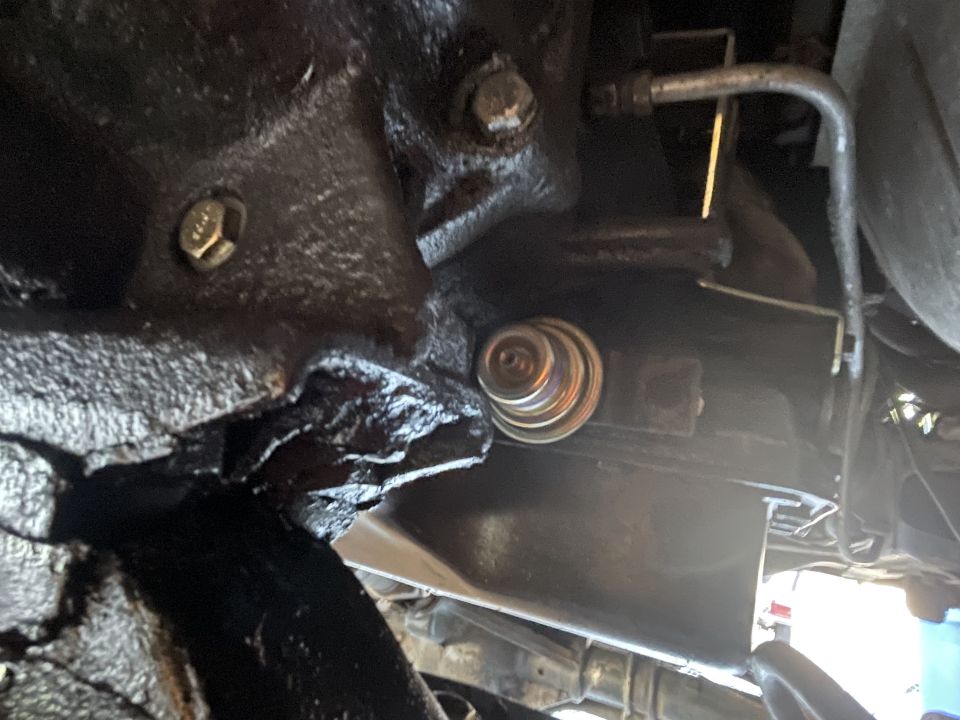 Underside of vehicle engine bay showing oil filter and bolt.