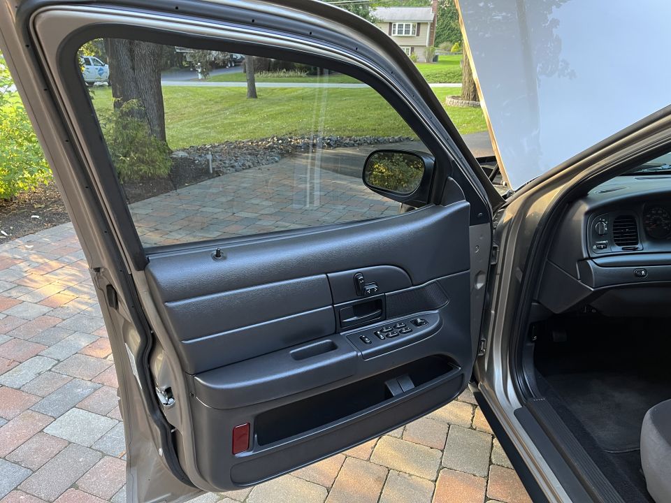 Open front car door showing door panel with power controls and dashboard