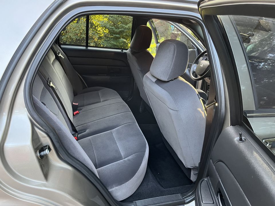Rear cloth bench seat of a Ford sedan viewed through open door