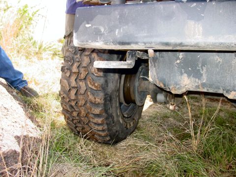 1973 Ford Bronco - A close-up view of the rear tire and bumper of a vehicle in an outdoor setting.