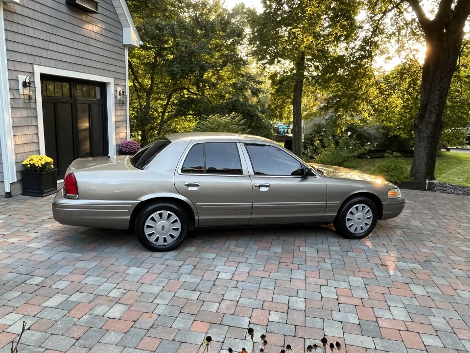 Passenger-side profile of a tan Ford Crown Victoria in a driveway
