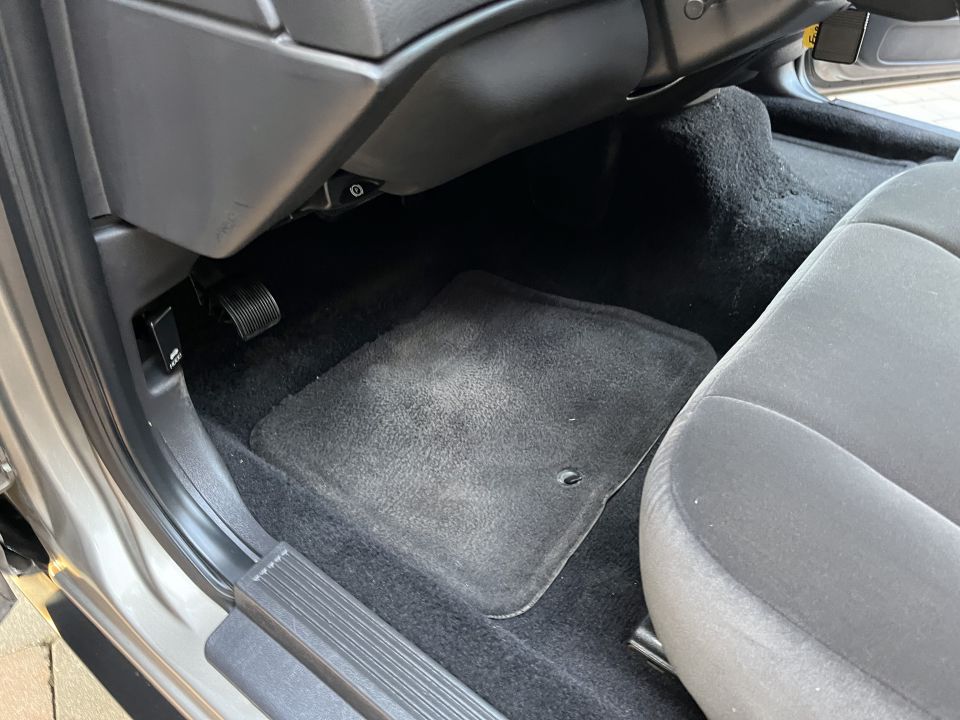 Photo of a vehicle front passenger footwell with floor mat and carpet