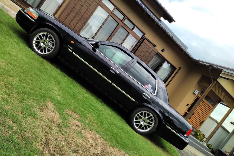 Black 2004 Mercury Grand Marquis parked on grass in front of a tan house.
