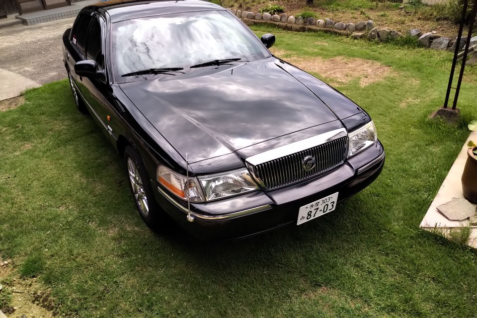 Black 2004 Mercury Grand Marquis parked on grass, front passenger side view.