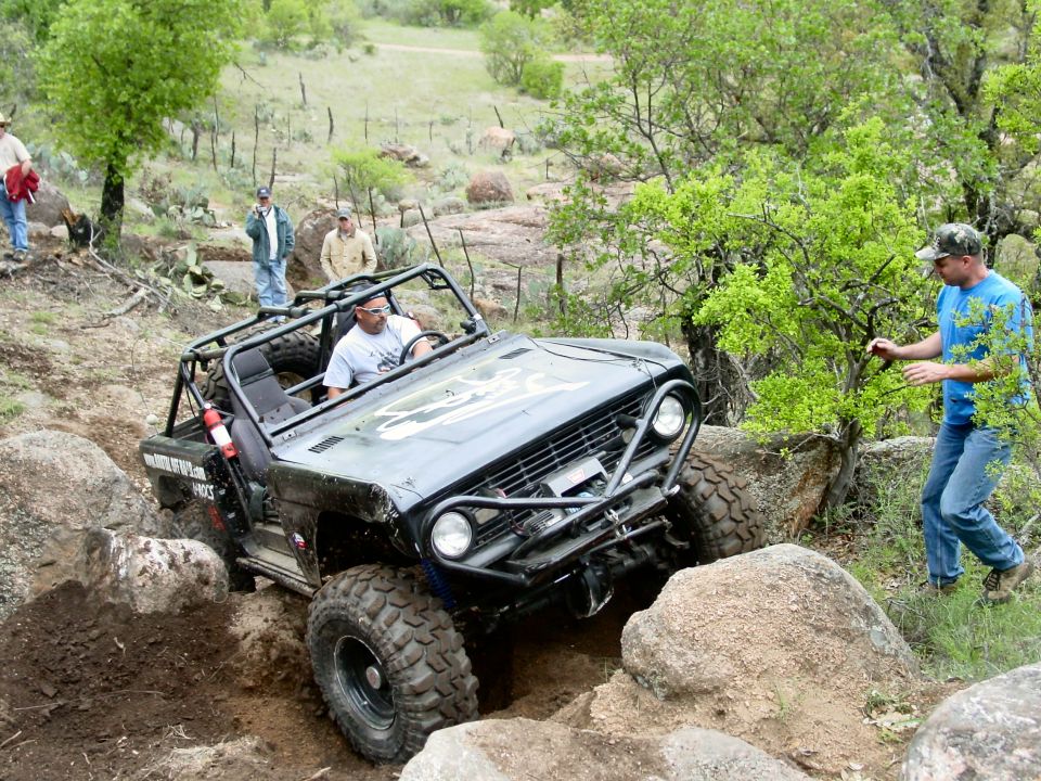 Black off-road vehicle with roll cage navigating rocky terrain