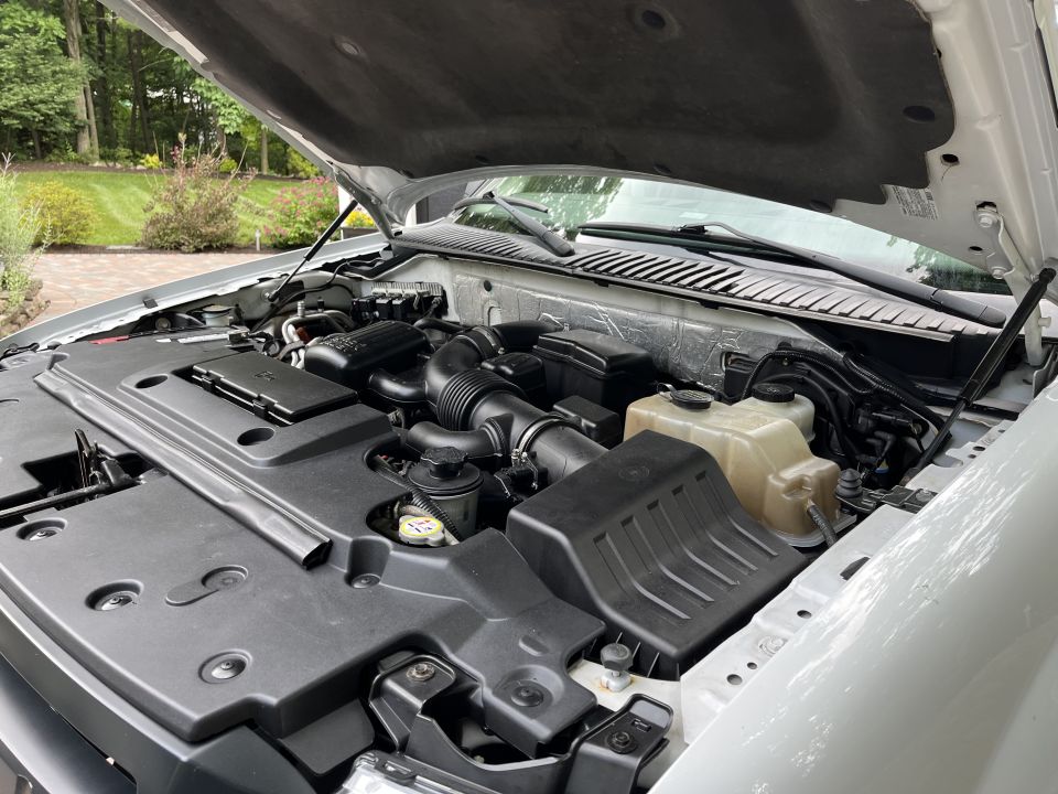 Open engine bay of a truck showing the engine and coolant reservoir