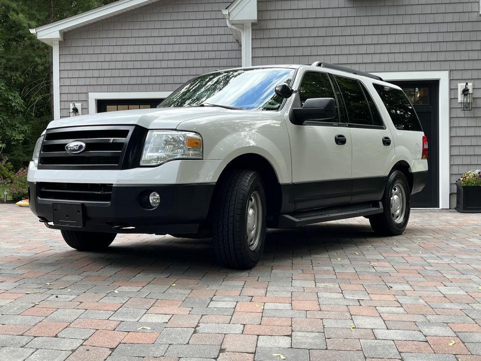 Front three-quarter view of white Ford Expedition by garage