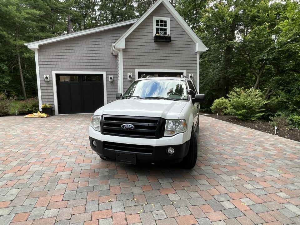 Front view of white Ford Expedition in front of garage