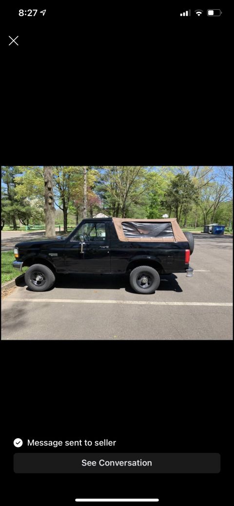 1994 Ford Bronco - This 1994 Ford Bronco is shown from the side, a black exterior and a tan soft top.