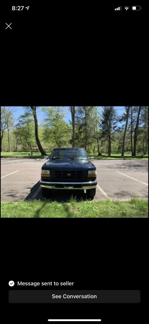 1994 Ford Bronco - This Ford F-150 pickup truck is parked in a lot surrounded by trees.