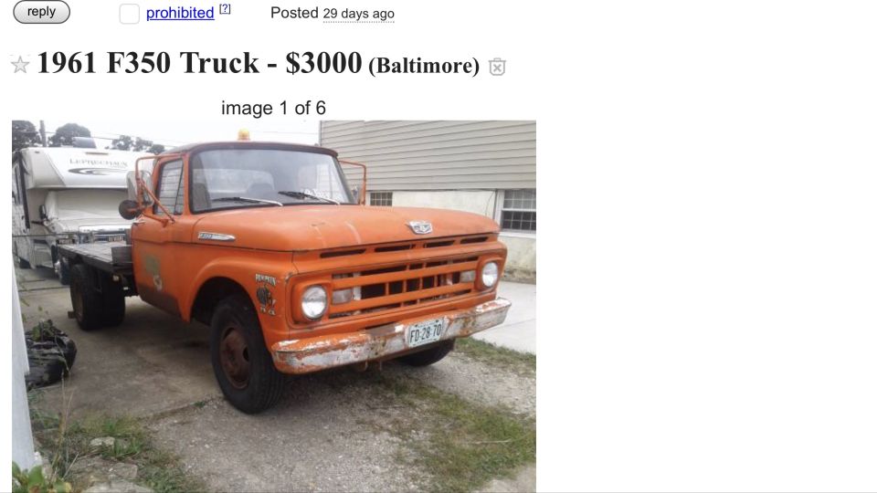 Orange flatbed truck with a camper on the back. License plate reads FD 28 70