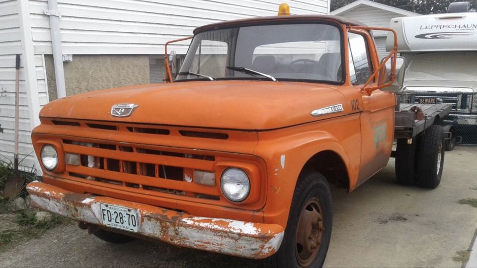 Orange 1961 Ford F-350 truck with a flatbed and dual rear wheels