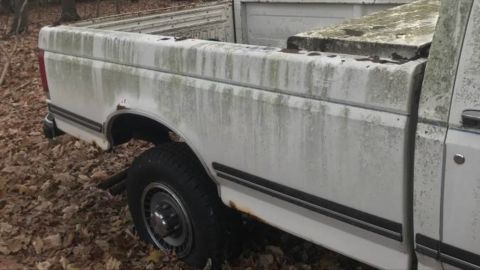 1989 Ford F-250 - A weathered white pickup truck sits outdoors, its side showing significant rust and dirt accumulation.