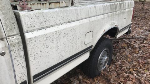 1989 Ford F-250 - Side view of a weathered white pickup truck, likely from the late 1980s, with visible wear and tear.