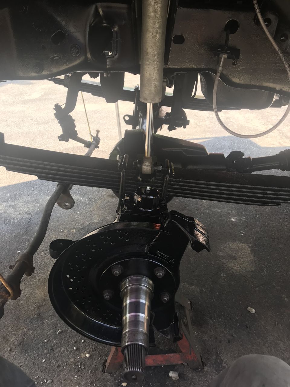 Truck's front axle, leaf springs, shock, and brake assembly are visible. The parts appear recently painted black