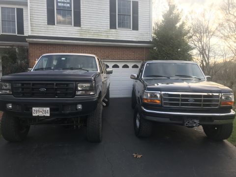1995 Ford F-150 - Two Ford trucks are parked side-by-side in a driveway, with one appearing to be lifted.